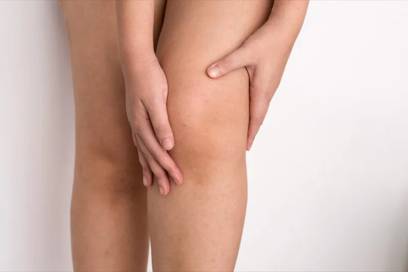 Patient holding their knee in pain before treatment